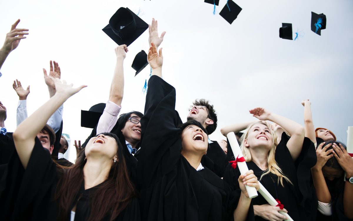 Group of diverse grads throwing caps up in the sky